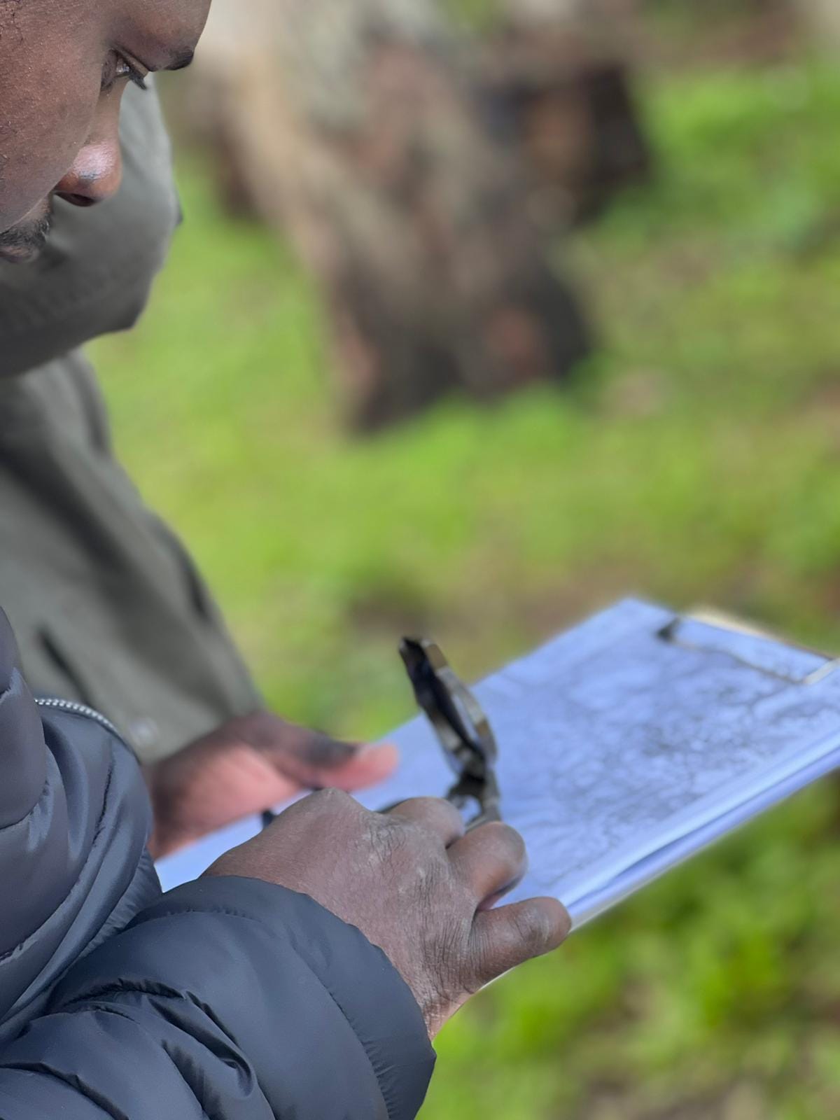 Man practicing navigation in the wild during survival training, using a map and compass to find his way