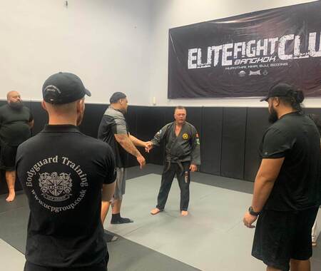 Trainer giving Muay Thai, Mixed Martial Arts, Brazilian Jiu-Jitsu, and boxing training to students in a focused martial arts class